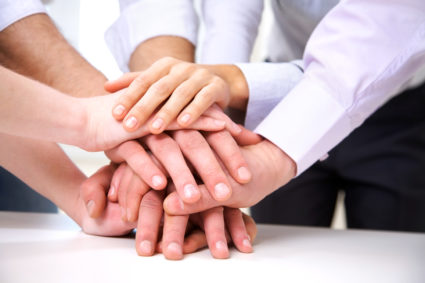 diverse group of workers with their hands together in form of teamwork